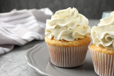 Tasty cupcakes with vanilla cream on grey table, closeup. Space for text