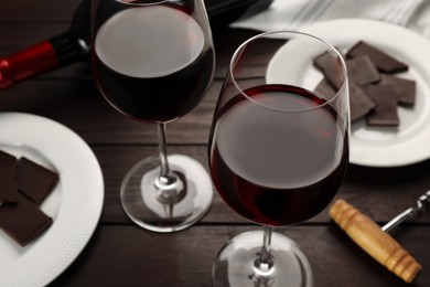 Photo of Tasty red wine and chocolate on wooden table, closeup