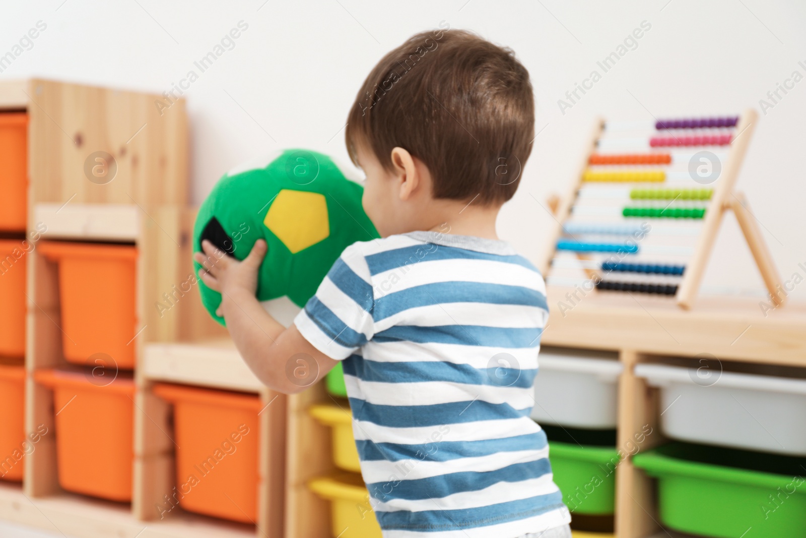 Photo of Little child playing with soft ball in room