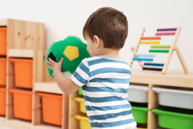 Little child playing with soft ball in room