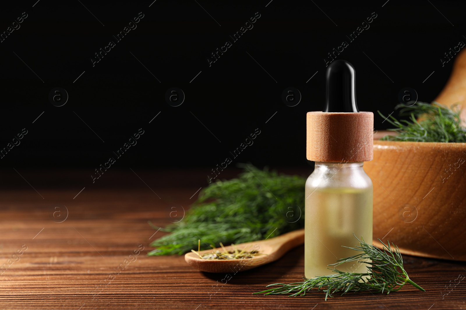 Photo of Bottle of essential oil and fresh dill on wooden table. Space for text