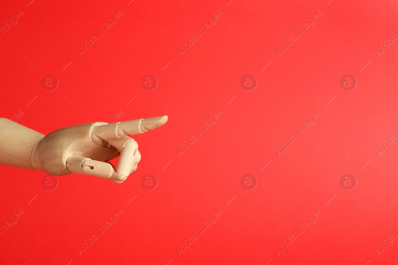 Photo of Wooden mannequin hand on red background. Space for text