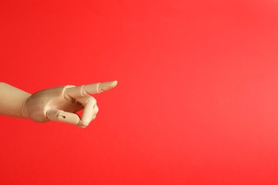 Wooden mannequin hand on red background. Space for text