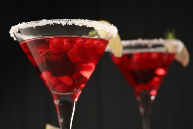 Photo of Tasty cranberry cocktail in glasses against black background, closeup