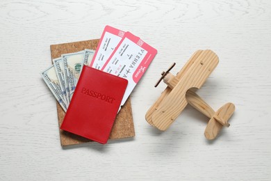 Flat lay composition with passport, tickets and model of plane on white wooden table. Business trip