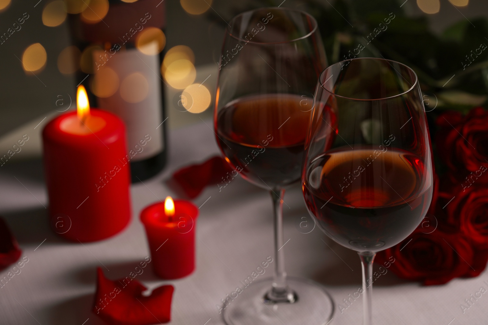 Photo of Romantic table setting with glasses of red wine, rose flowers and burning candles