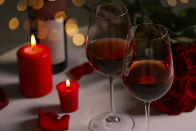 Photo of Romantic table setting with glasses of red wine, rose flowers and burning candles