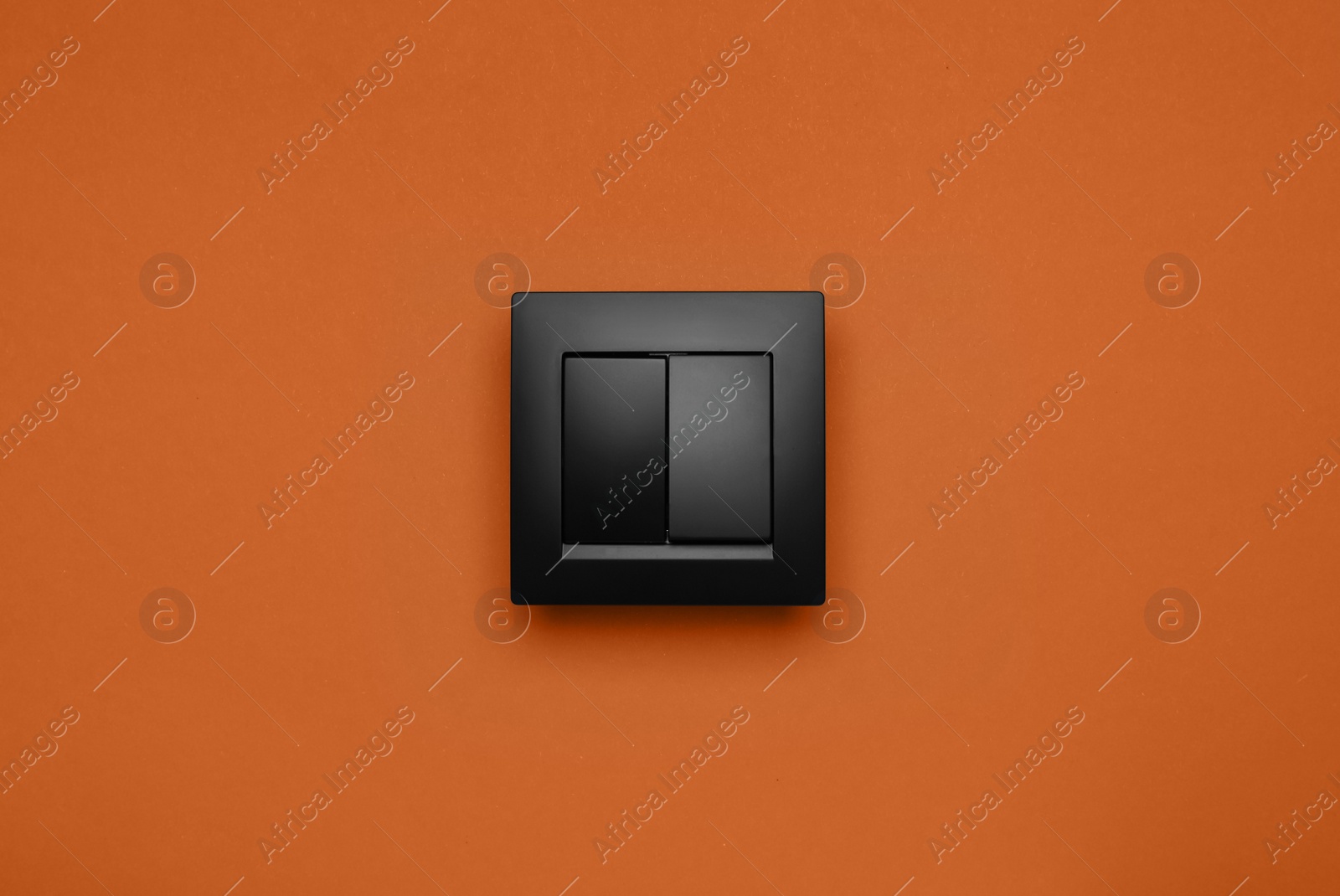 Photo of Black plastic light switch on orange background