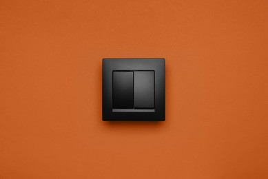 Photo of Black plastic light switch on orange background