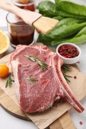 Photo of Raw meat, rosemary and products on white table, closeup