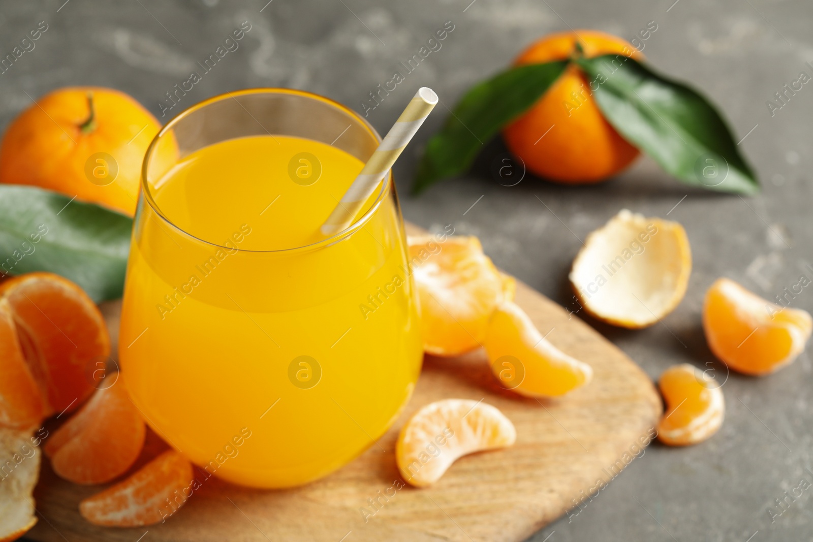 Photo of Fresh tangerines and glass of juice on grey table