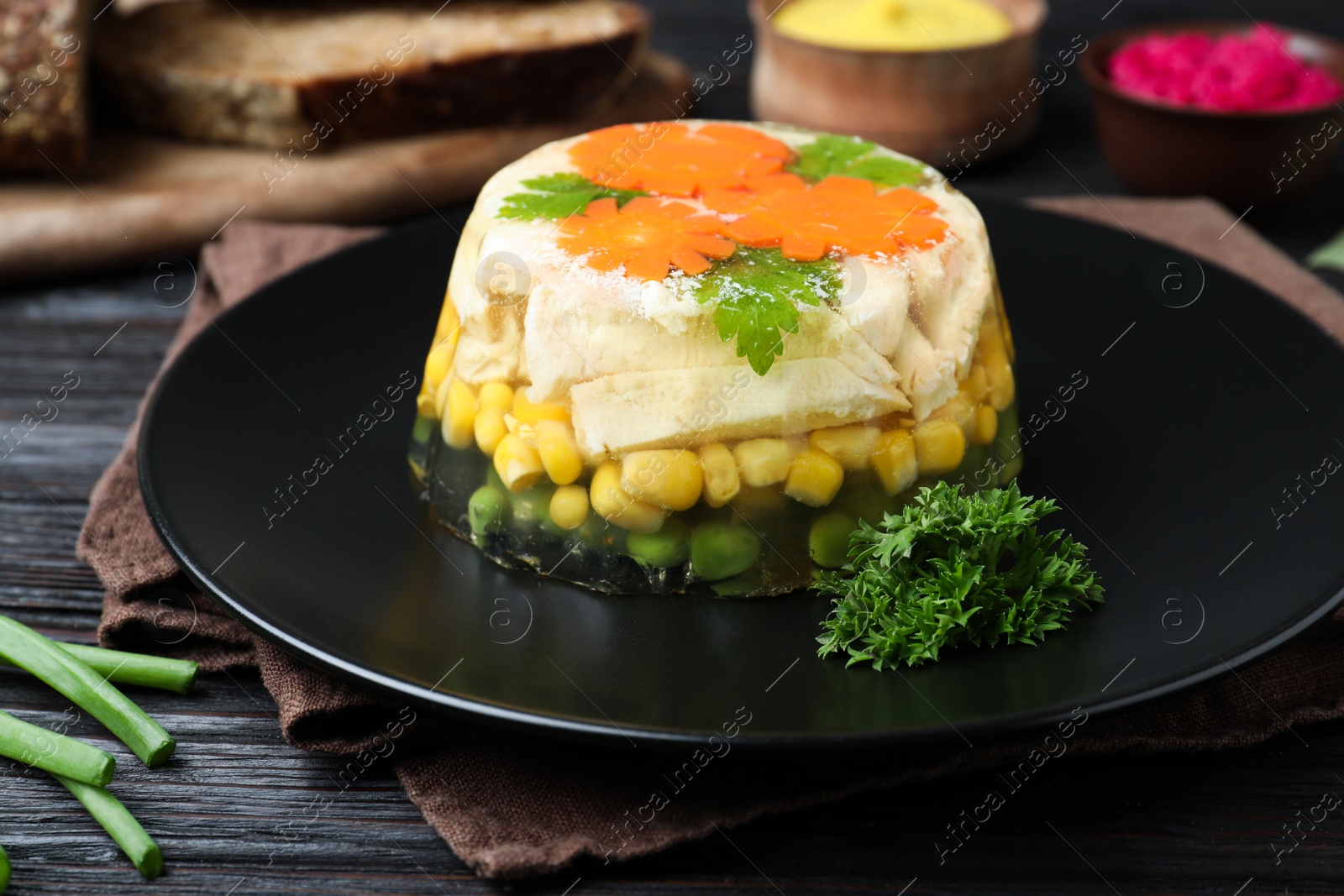 Photo of Delicious homemade chicken aspic on black wooden table, closeup