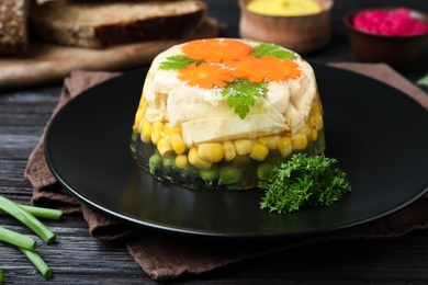 Photo of Delicious homemade chicken aspic on black wooden table, closeup