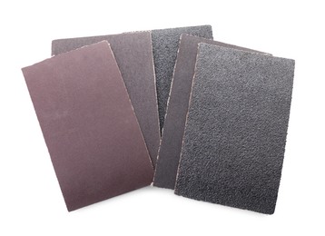 Photo of Many sheets of sandpaper isolated on white, top view