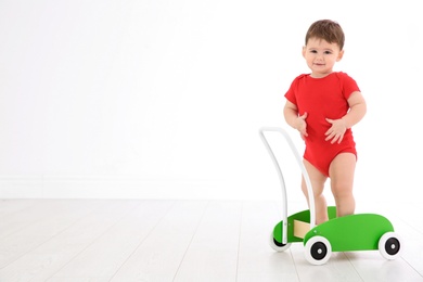 Photo of Cute baby playing with toy walker, indoors