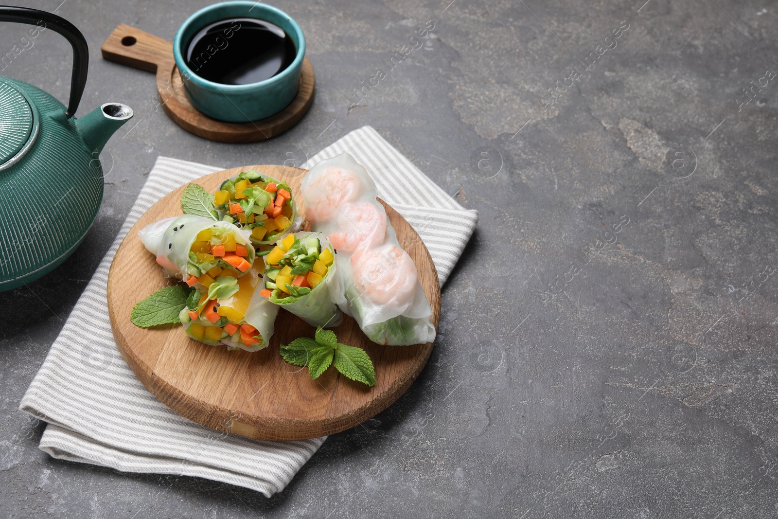 Photo of Tasty spring rolls on grey textured table, closeup. Space for text