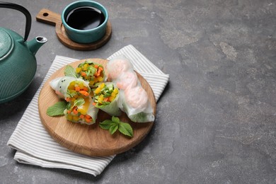 Photo of Tasty spring rolls on grey textured table, closeup. Space for text