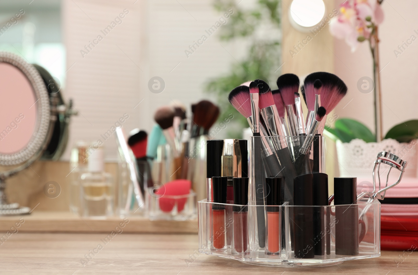 Photo of Organizer with cosmetic products for makeup on table near mirror. Space for text