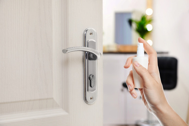 Image of Woman sanitizing door handle with antiseptic spray, closeup. Be safety during coronavirus outbreak