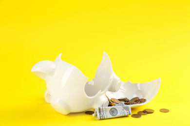Photo of Broken piggy bank with money on yellow background
