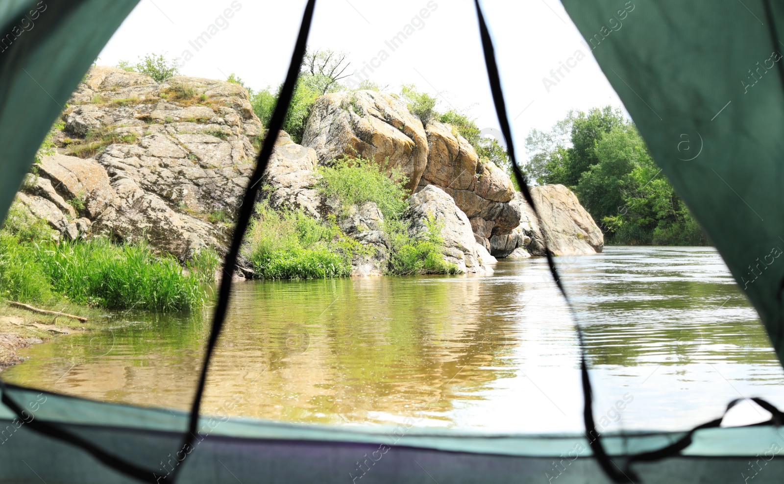 Photo of Calm river with rocky bank, view from camping tent