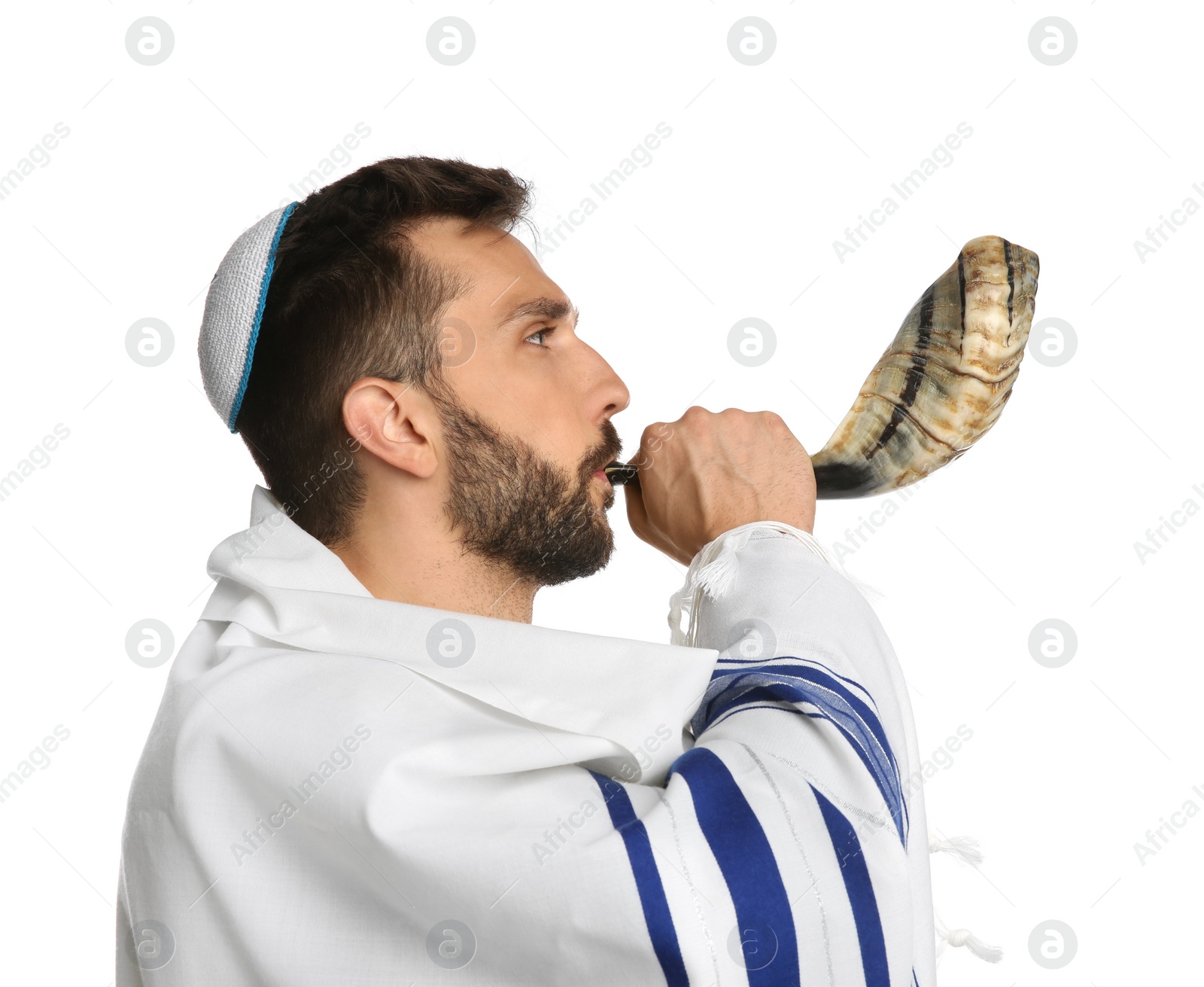 Photo of Jewish man with kippah and tallit blowing shofar on white background. Rosh Hashanah celebration