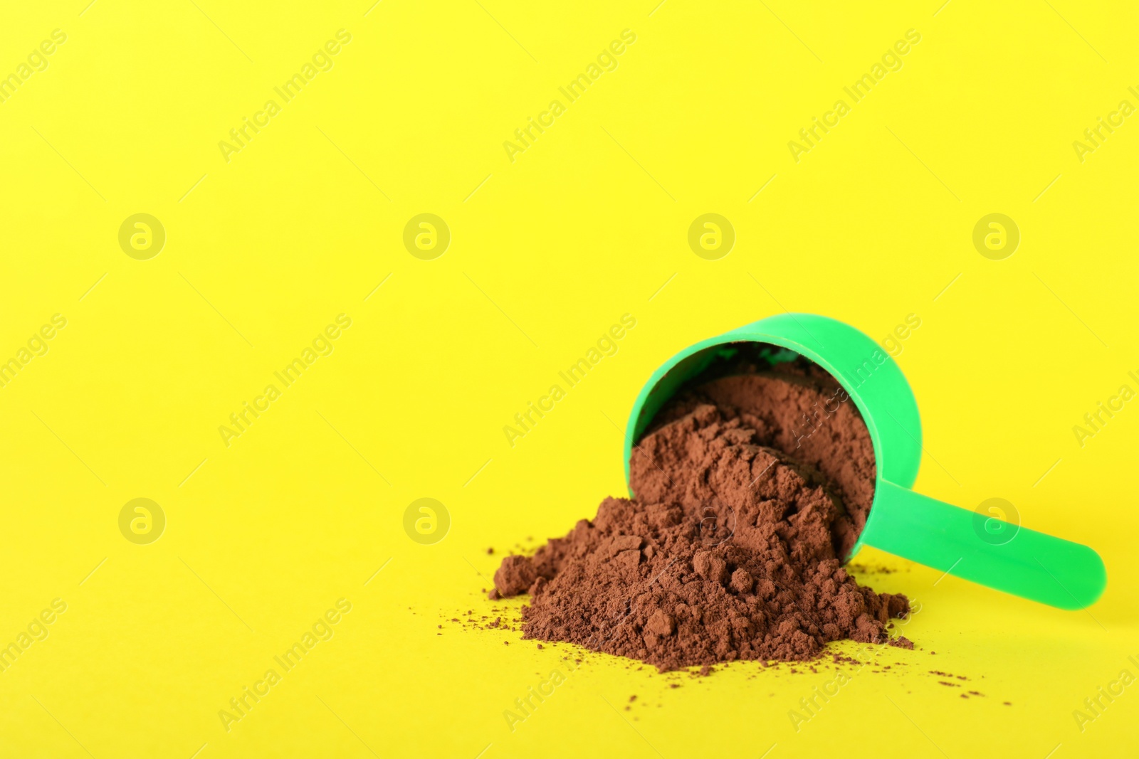 Photo of Scoop and scattered protein powder on yellow background, space for text