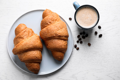 Photo of Fresh croissants and coffee on white wooden table, flat lay