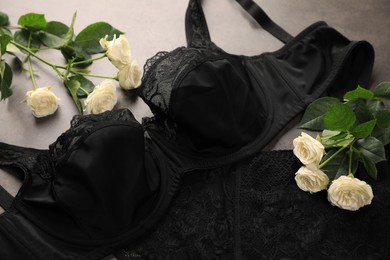 Photo of Elegant black plus size women's underwear and beautiful roses on grey background, closeup