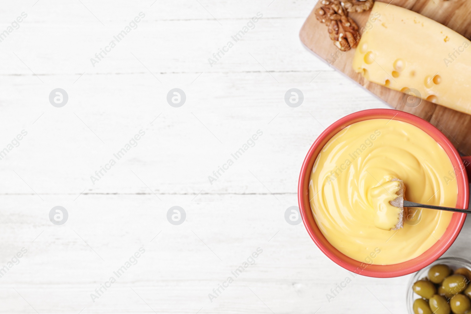 Photo of Flat lay composition with pot of cheese fondue and products on white wooden table, space for text