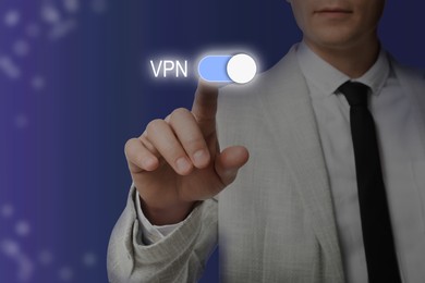 Man and switched on VPN button on color background, closeup