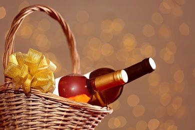 Photo of Bottles of wine in wicker basket with bow against blurred lights