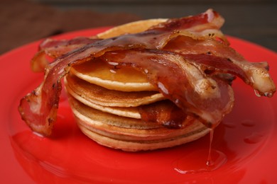 Delicious pancakes with bacon and honey on table, closeup