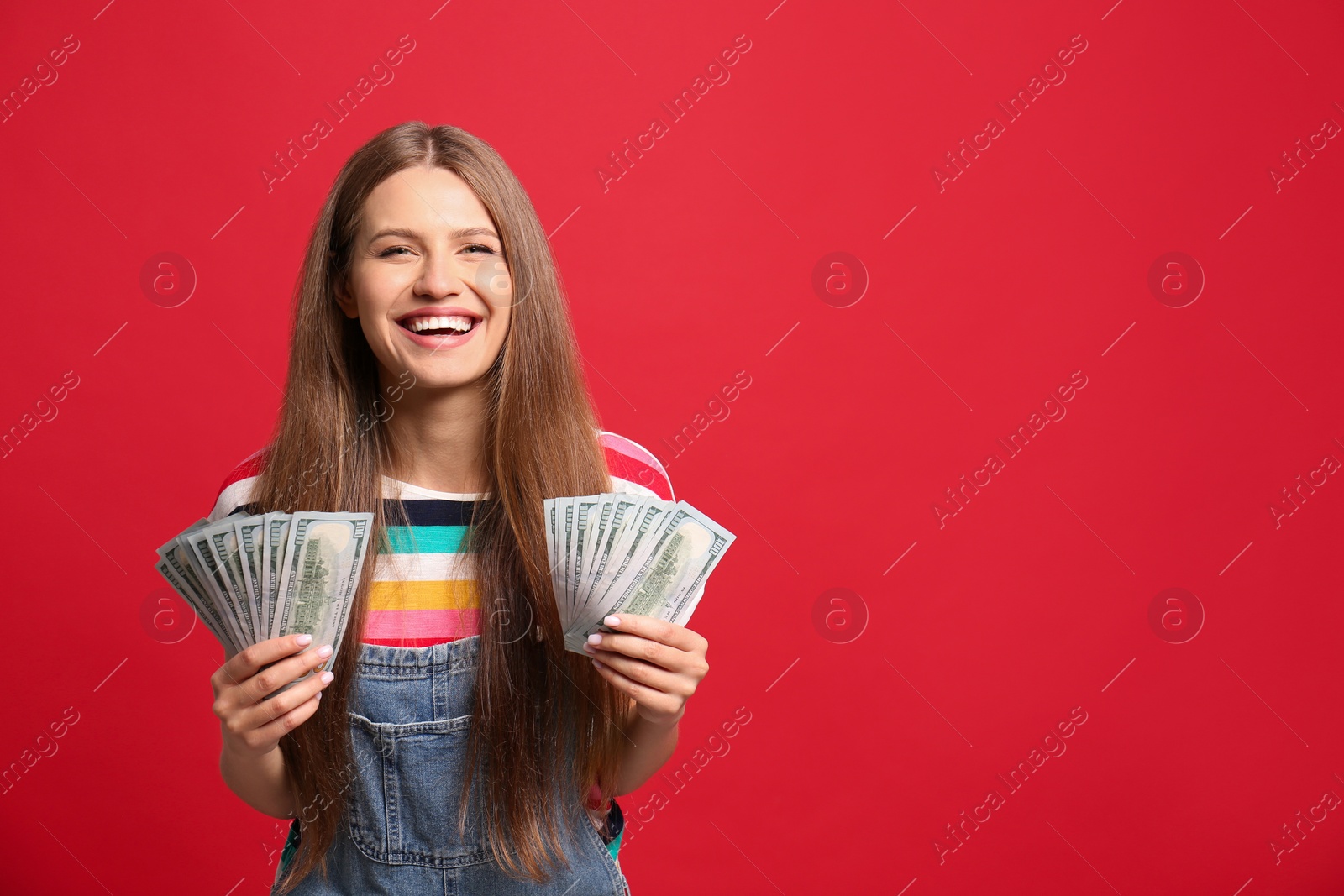Photo of Portrait of happy lottery winner with money on red background, space for text