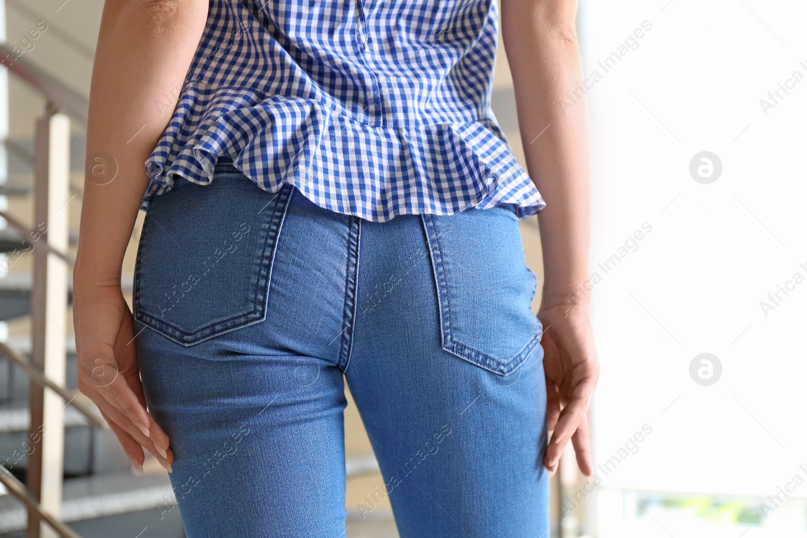 Photo of Young woman in stylish blue jeans indoors