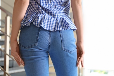 Photo of Young woman in stylish blue jeans indoors