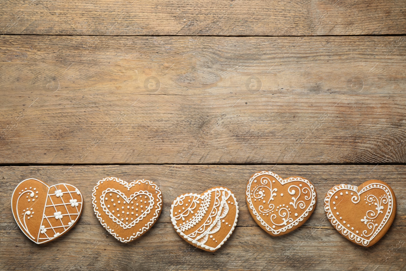 Photo of Decorated gingerbread hearts on wooden table, flat lay. Space for text