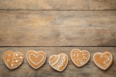 Photo of Decorated gingerbread hearts on wooden table, flat lay. Space for text