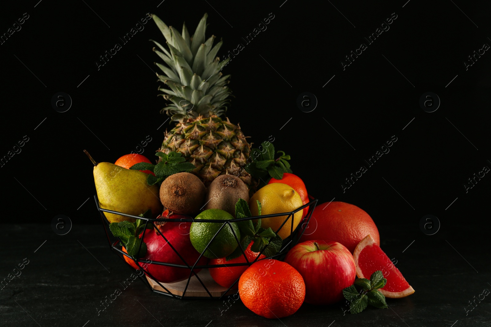 Photo of Fresh ripe fruits and metal bowl on black table