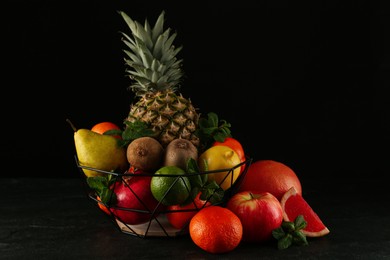 Photo of Fresh ripe fruits and metal bowl on black table