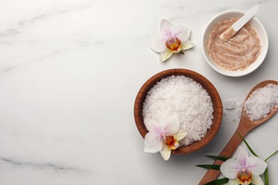 Flat lay composition with different spa products and flowers on white marble table. Space for text