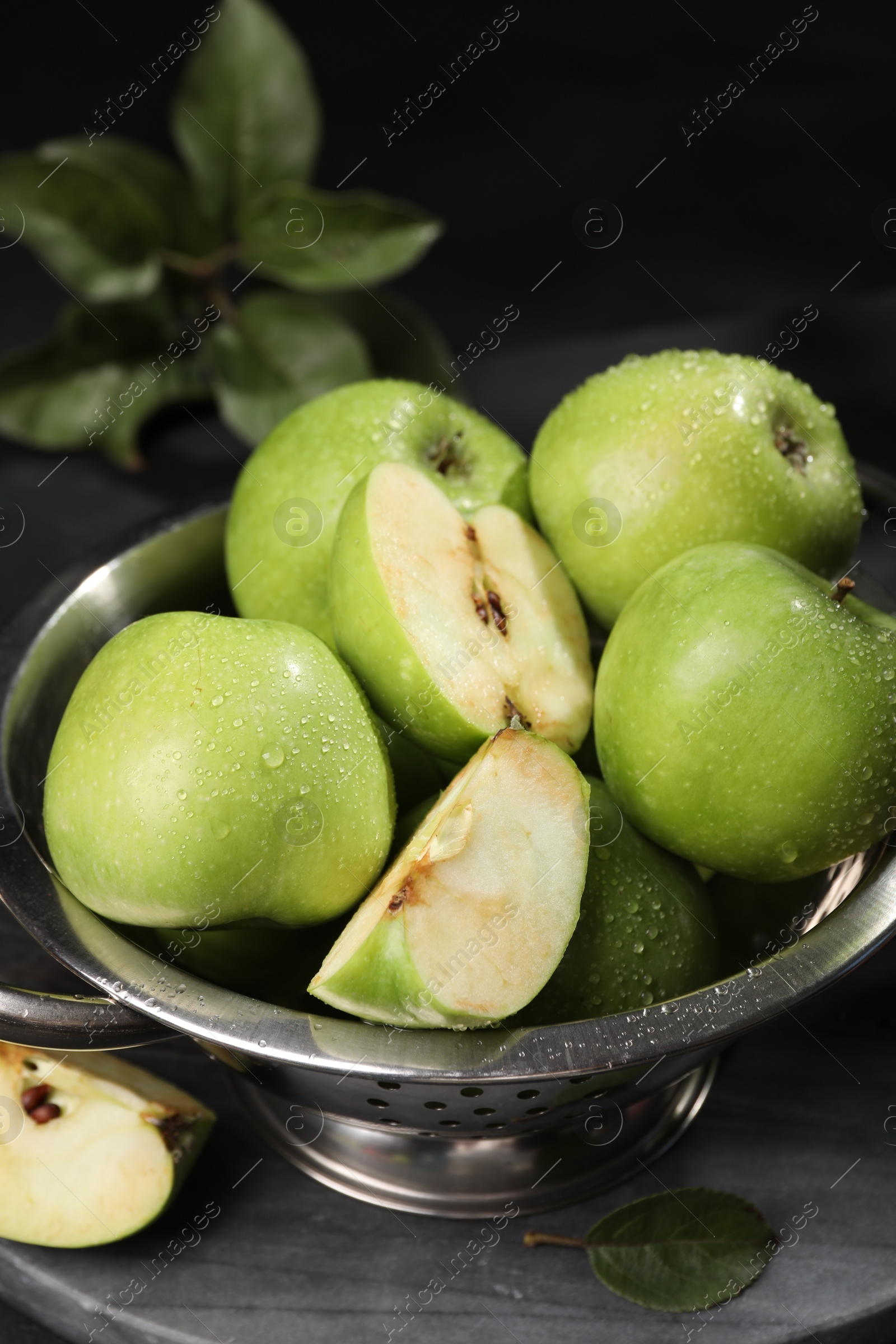 Photo of Ripe green apples with water drops and colander on table