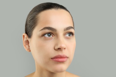 Photo of Young woman with perfect eyebrows on grey background