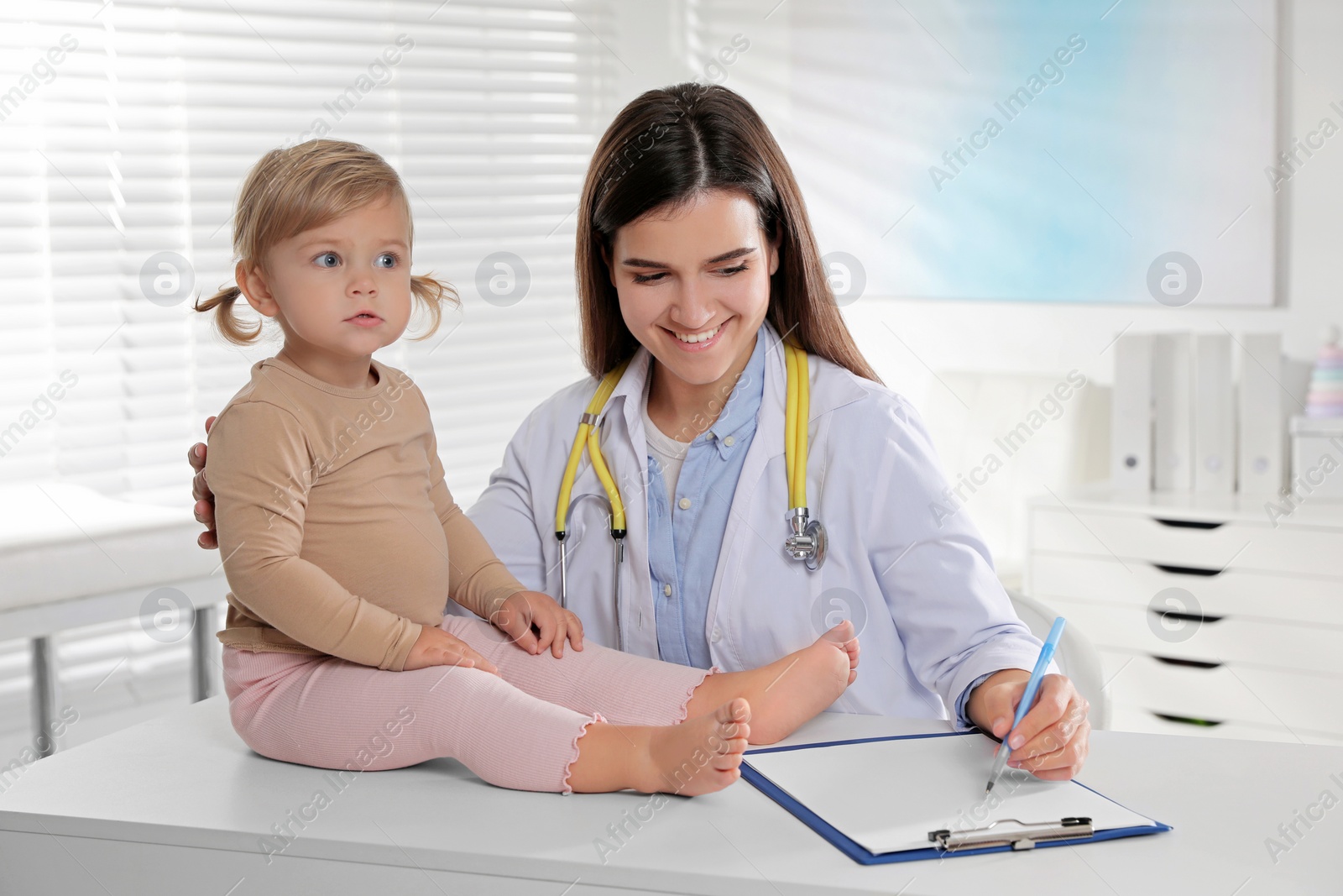 Photo of Pediatrician examining cute little baby in clinic