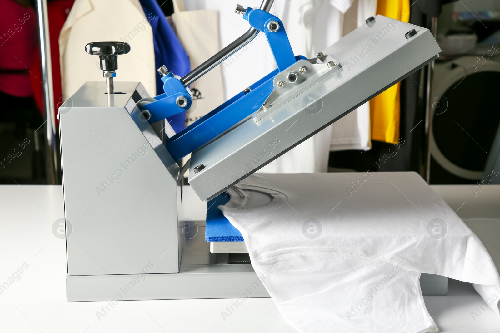 Photo of Printing logo. Heat press with t-shirt on white table