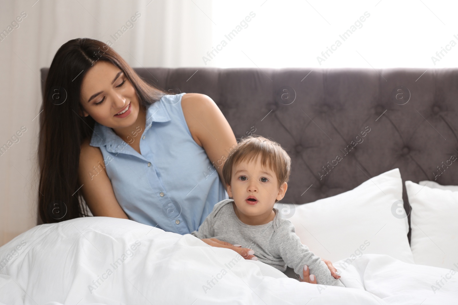 Photo of Young nanny with cute little baby in bedroom