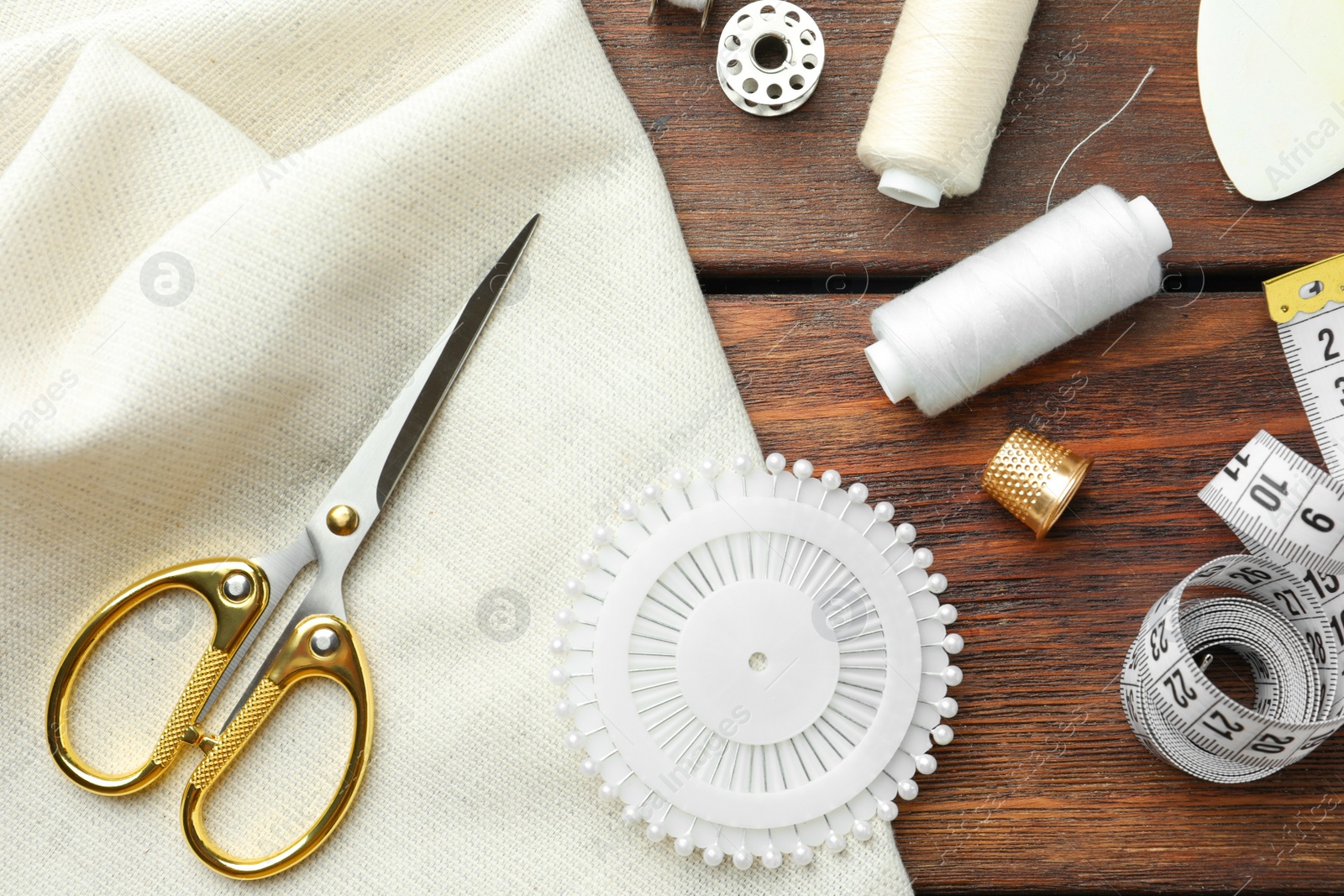 Photo of Threads and other sewing supplies on wooden table, flat lay