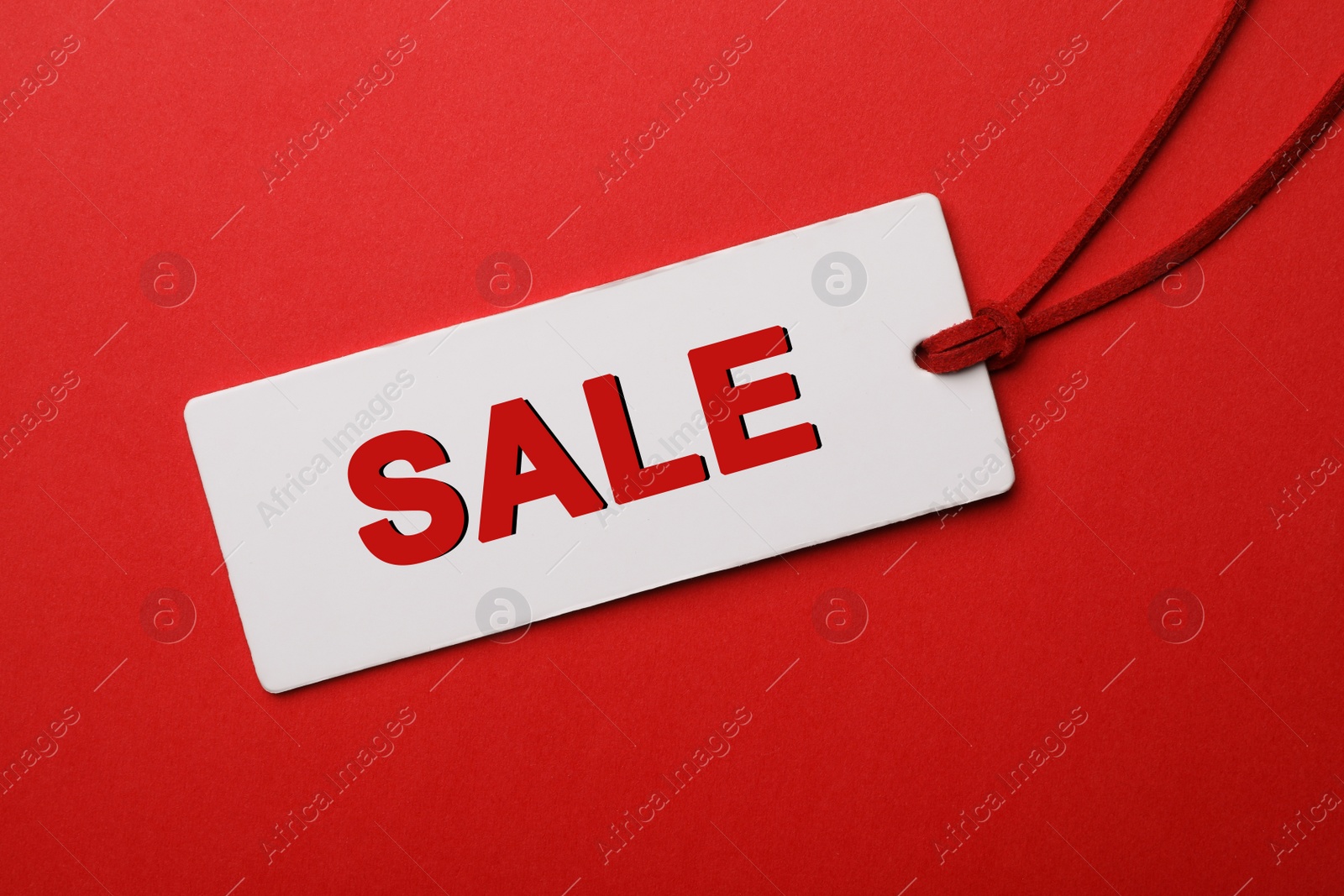 Image of Tag with text SALE on red background, top view. Black Friday 