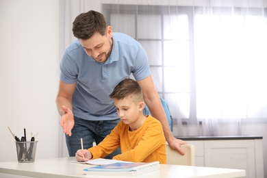 Dad helping his son with homework in room, space for text
