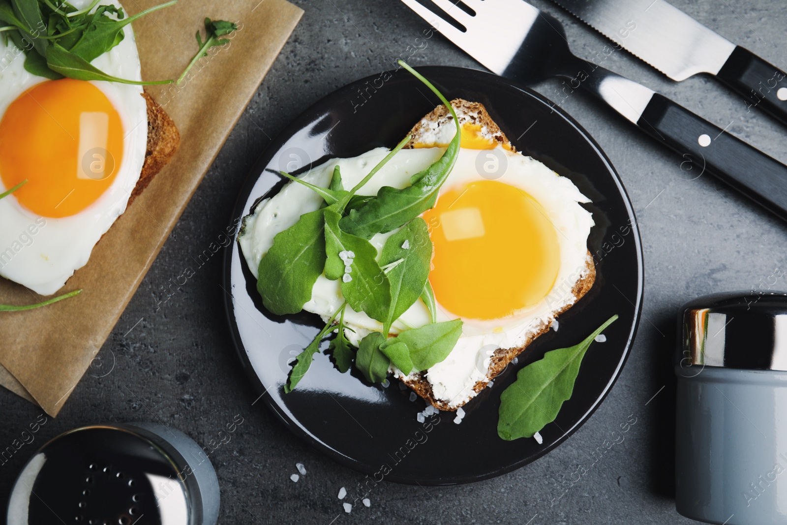 Photo of Delicious sandwich with arugula and fried egg on grey table, flat lay